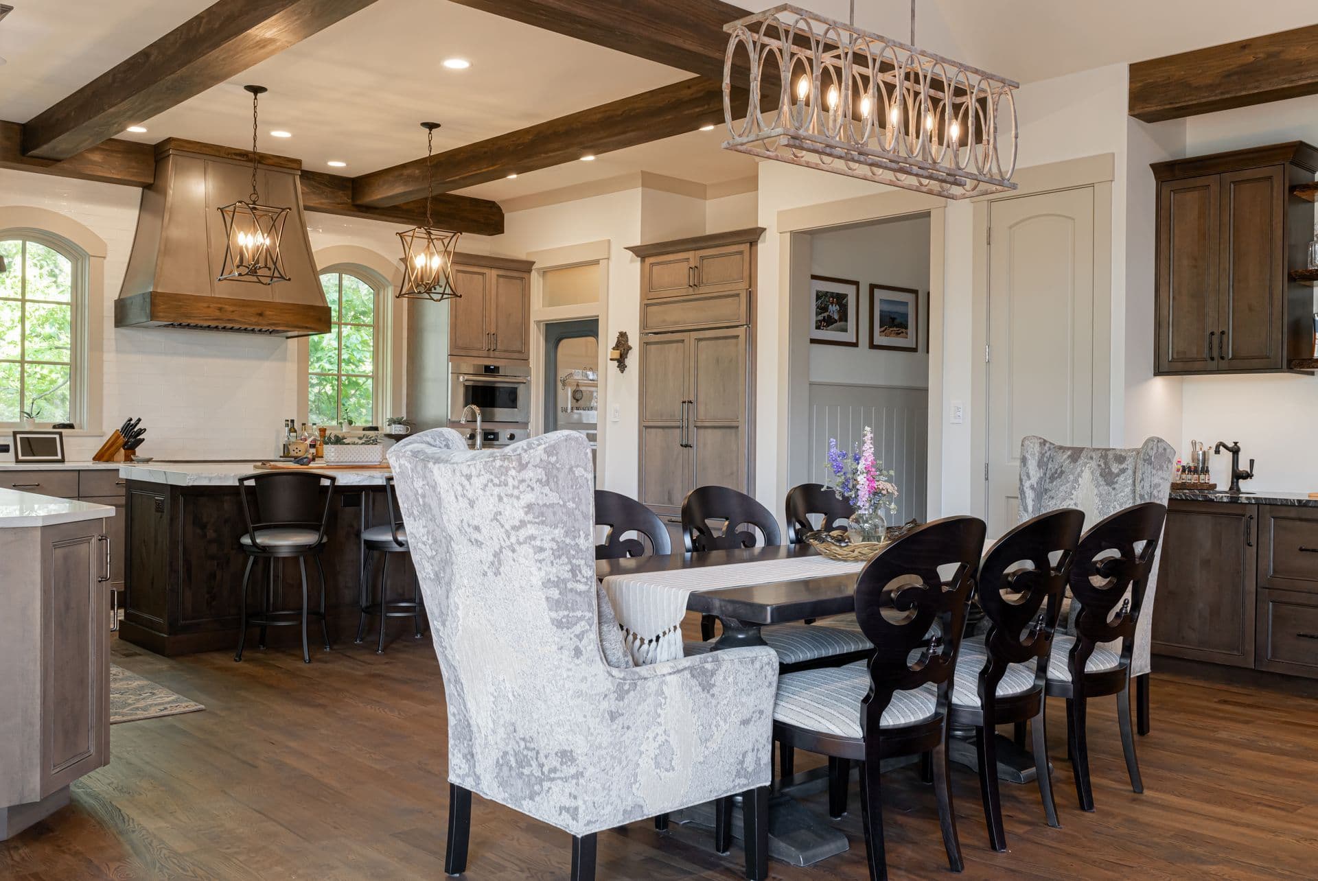 French country dining room with a long table, upholstered chairs and a warm, light-filled kitchen