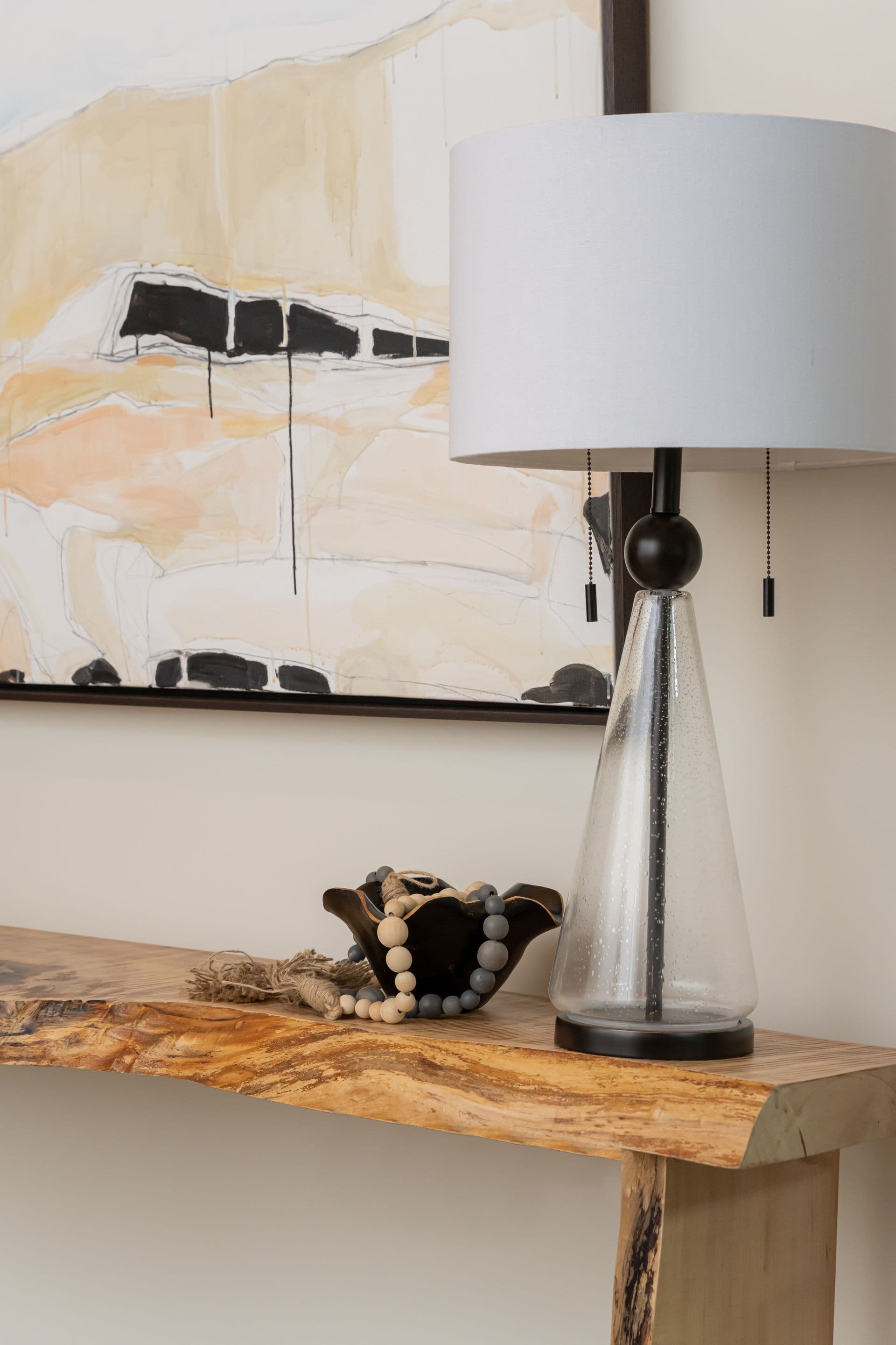 Live-edge console with a table lamp and abstract artwork