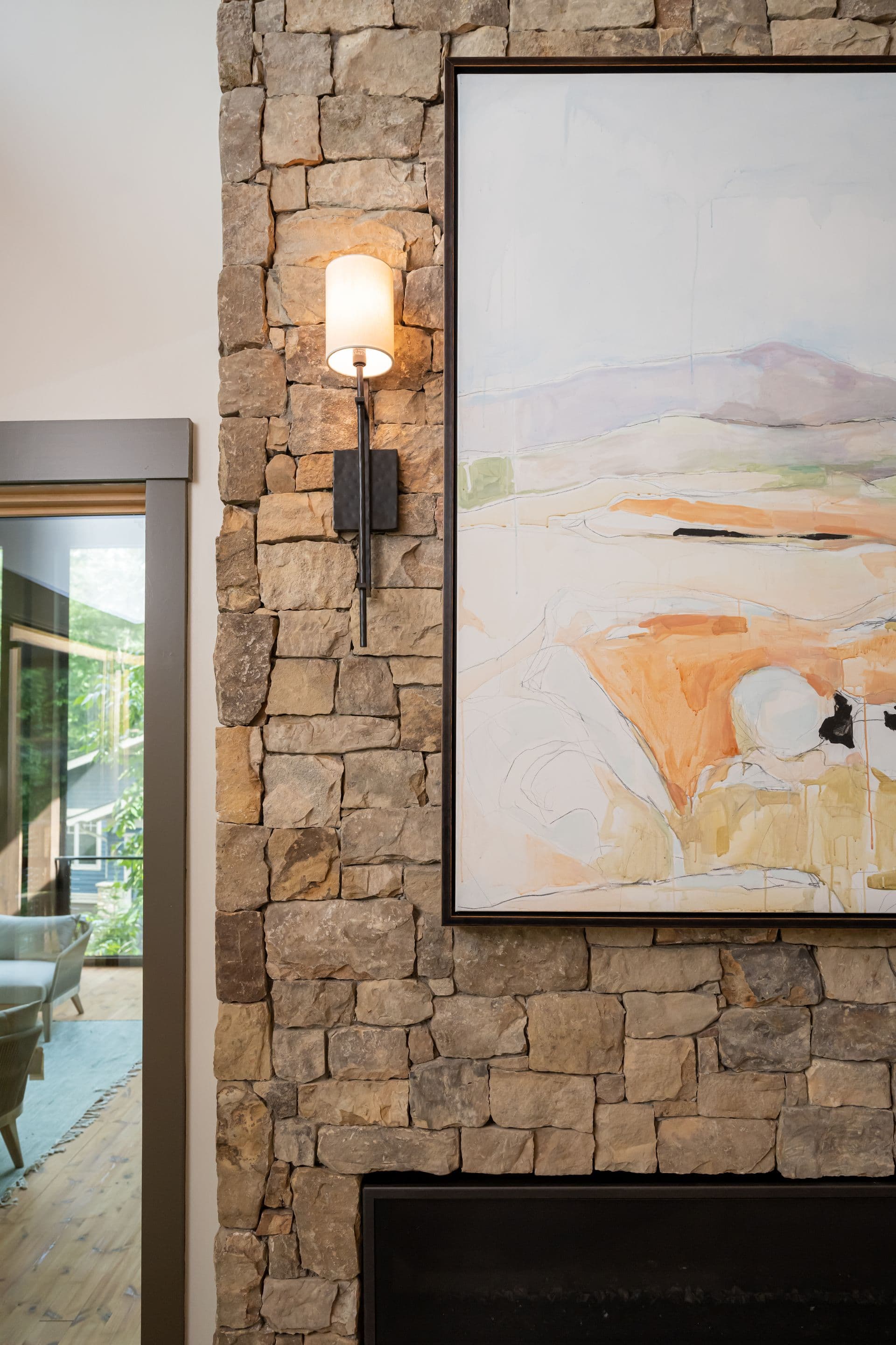 Stone wall with a softly lit sconce and framed landscape artwork