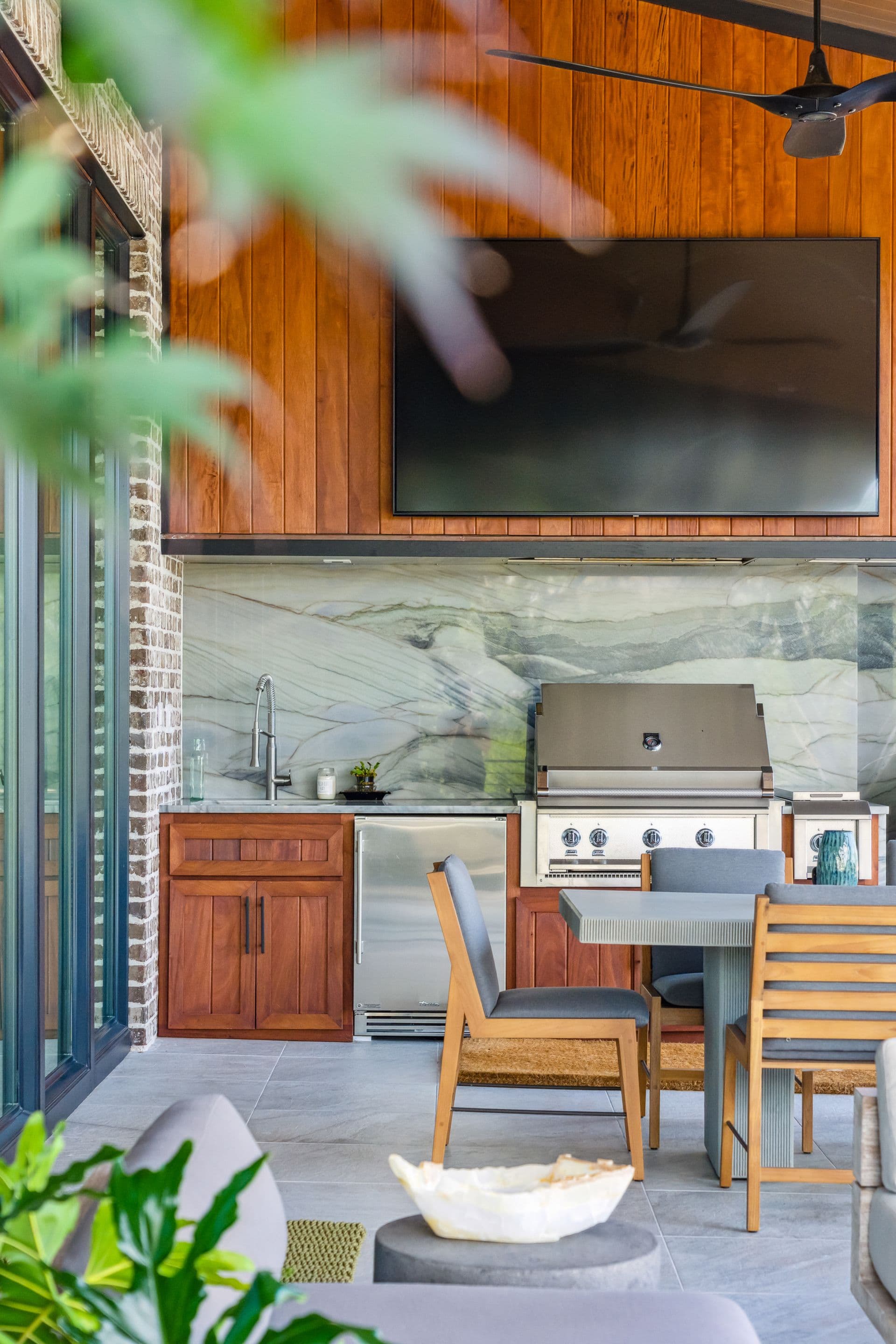 Outdoor kitchen and dining space framed by greenery