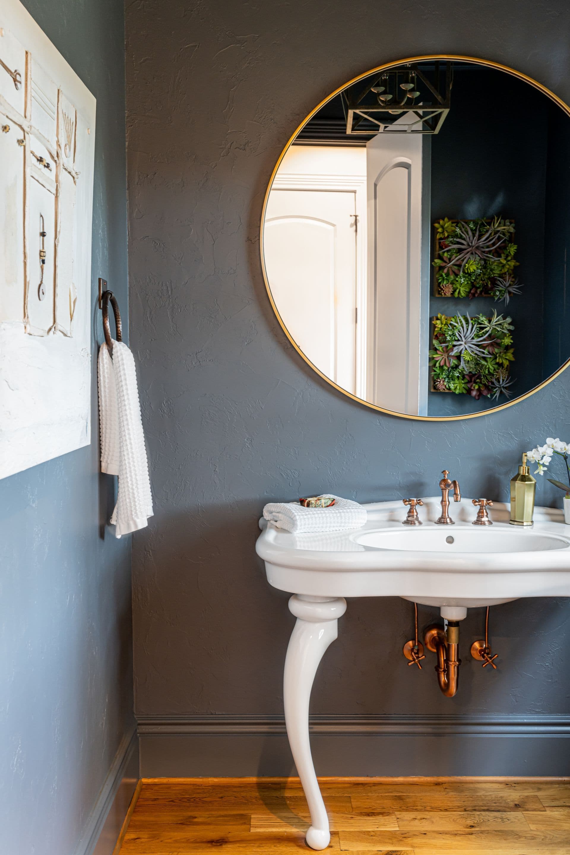Powder room with a round mirror and sculptural pedestal sink