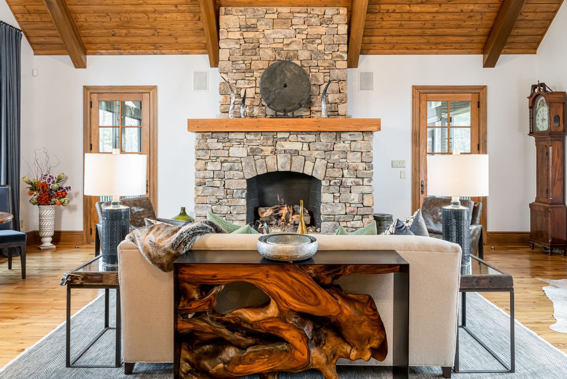 A mountain home living room with a stone fireplace and timber ceiling
